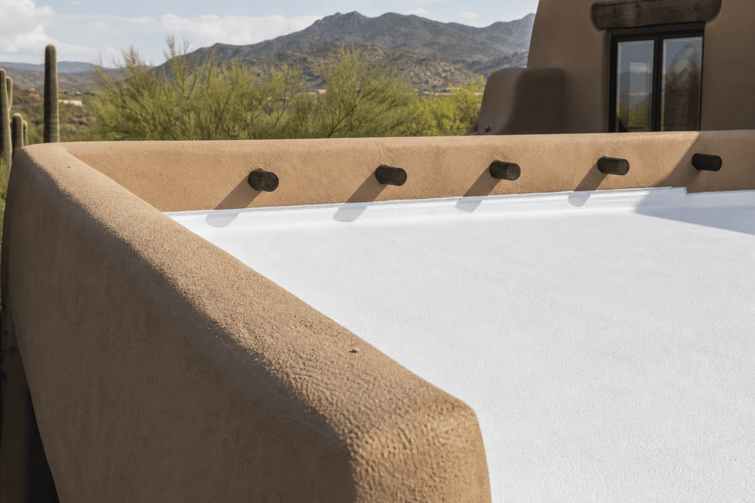 Clean foam roof recoat detail on a low-slope Pueblo Revival roof section.